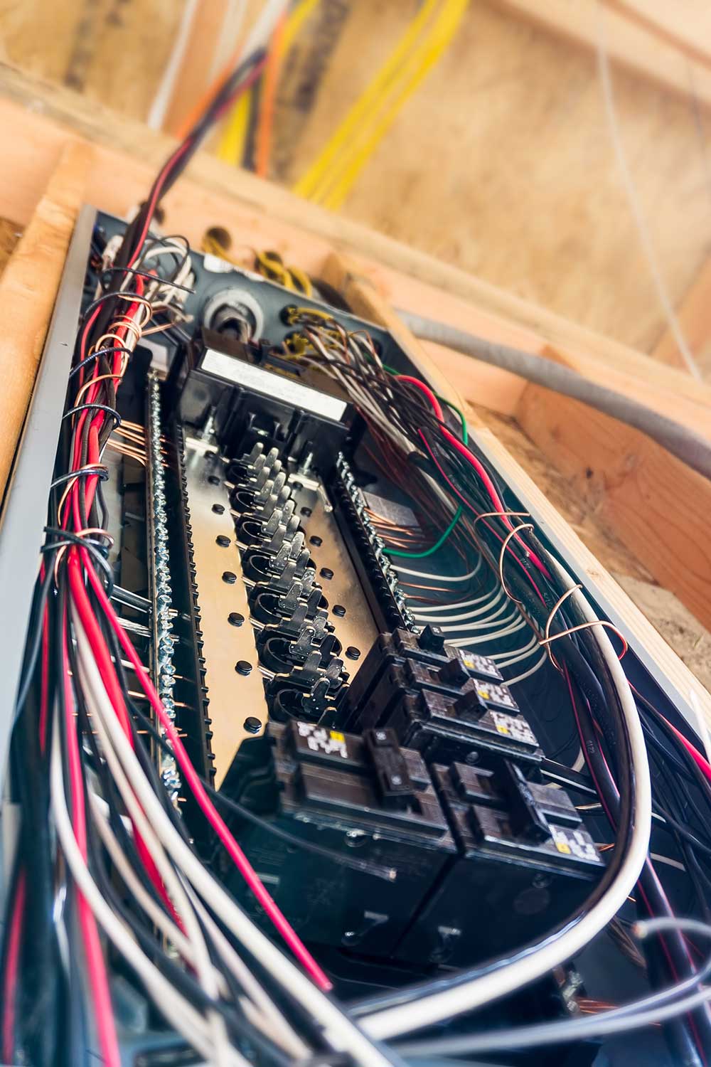Close-up of a tangled array of wires and circuit breakers inside an electrical panel.