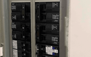 Inside a residential breaker panel with numerous circuit breakers in a metal box.