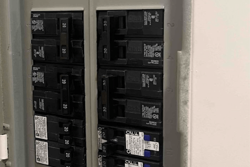 Inside a residential breaker panel with numerous circuit breakers in a metal box.