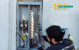 Electrician works on an outdoor electrical service panel/disconnect.