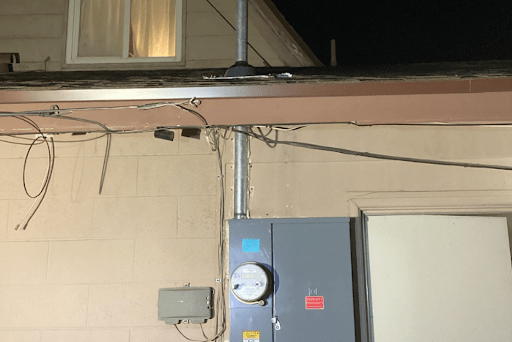 Close-up of exterior electrical setup: conduit, meter, and scattered wires.