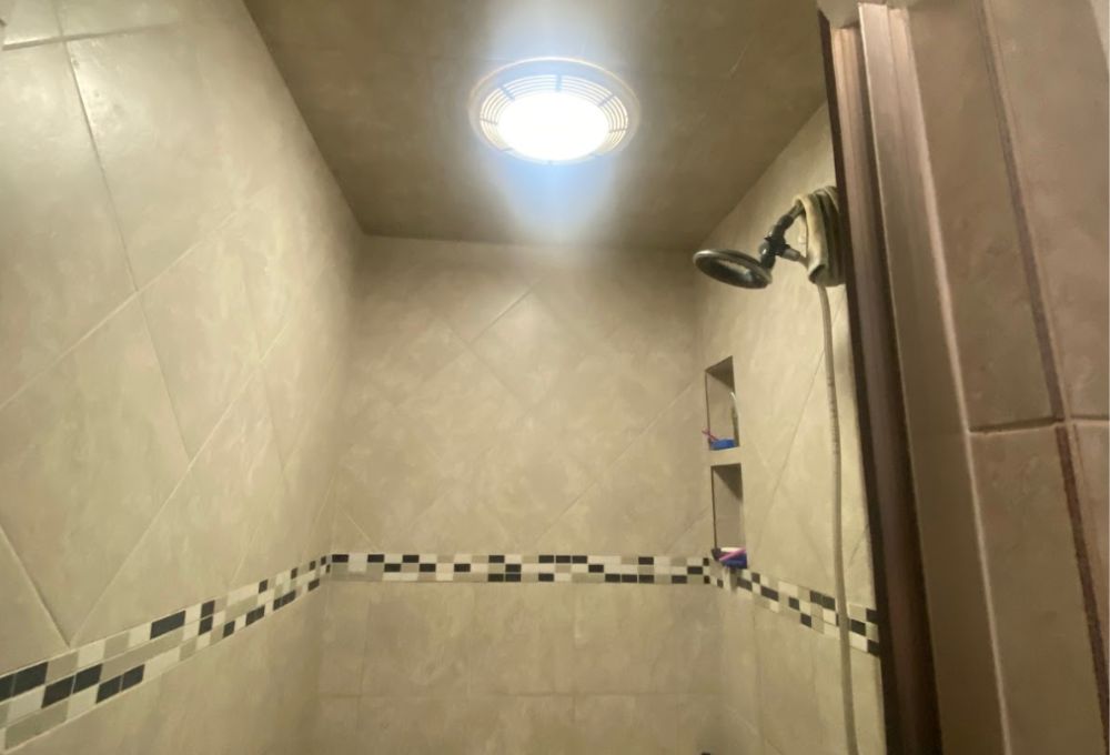 image_10 Walk-in shower with beige tile, a decorative border, and a ceiling light.